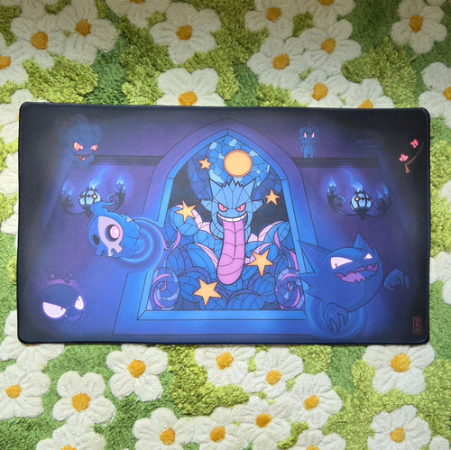 A photo of a blue and purple ghost themed playmat laying on a green and white daisy carpet.