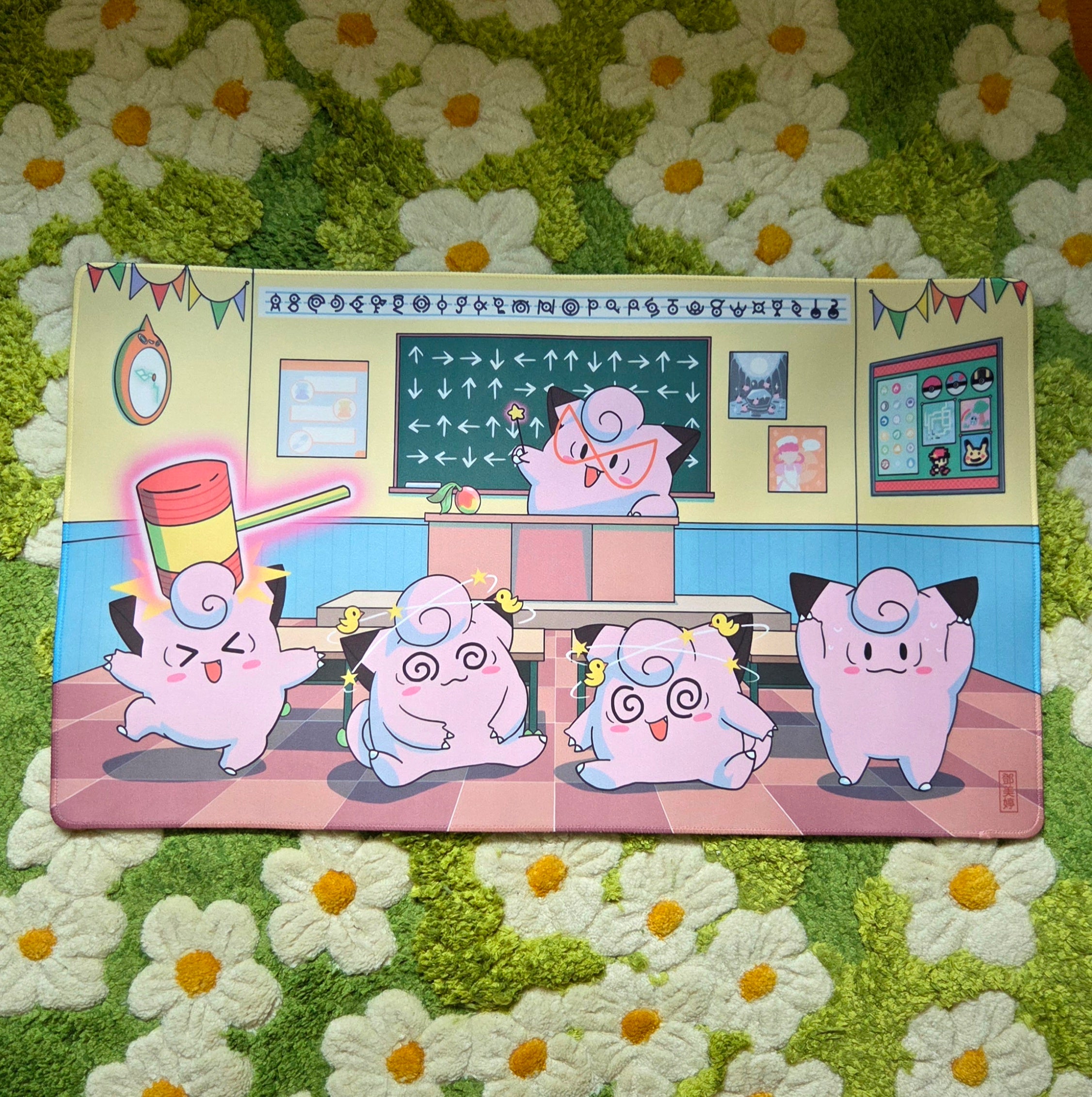 A photo of a yellow, blue, and pink classroom themed playmat laying on a green and white daisy carpet.