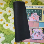 A photo of a yellow, blue, and pink classroom themed playmat laying on a green and white daisy carpet. The edge of the mat is flipped over to display a black textured rubber underside.